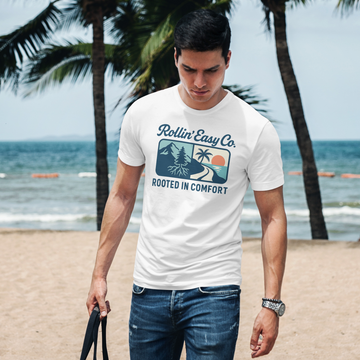 Man wearing a 'Rollin' Easy Co. Rooted in Comfort' t-shirt on a beach.